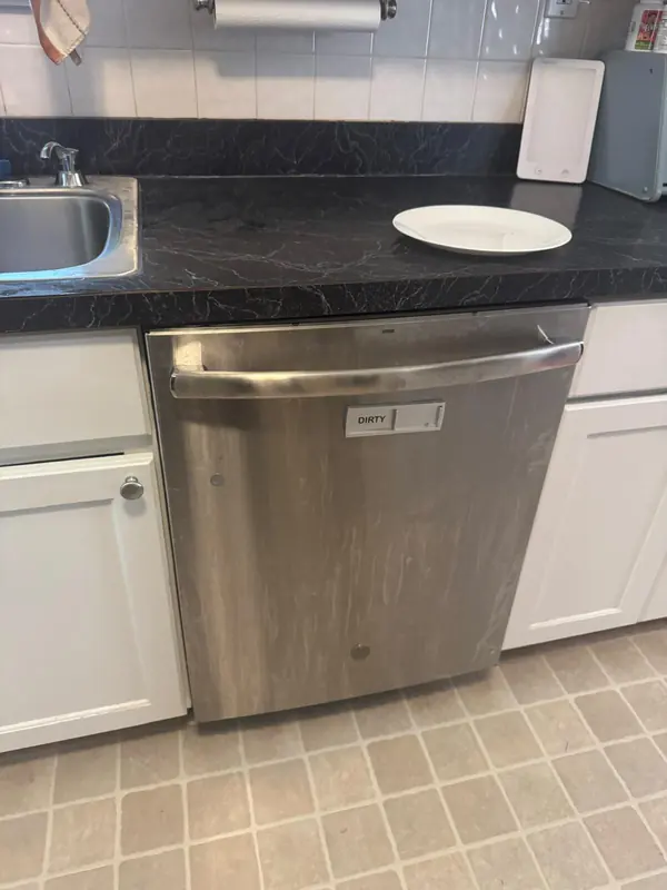 Stainless steel built-in dishwasher under a kitchen counter at the start of a service call