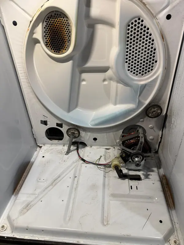 Dryer cabinet with the drum removed, showing the drum support rollers, the idler pulley and the drive motor