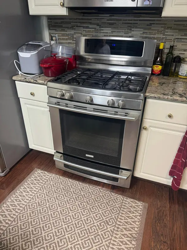 Stainless five-burner gas range with a backguard display, under an over-the-range microwave