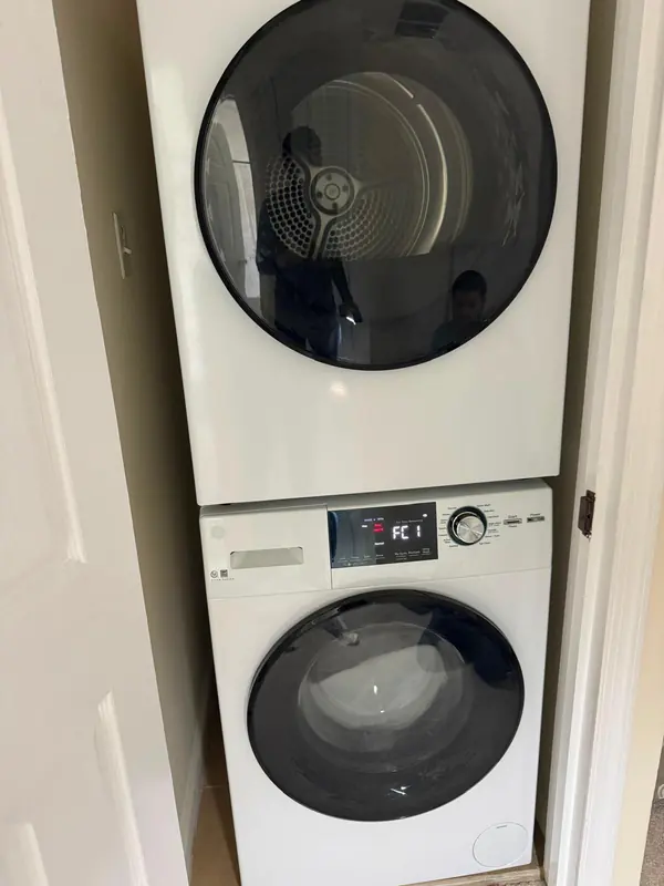 GE front-load washer stacked under a dryer in a laundry closet, the display showing FC1 with the door locked