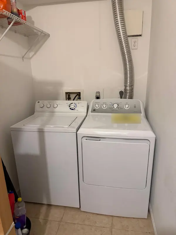 GE top-load washer and GE dryer side by side in a laundry closet
