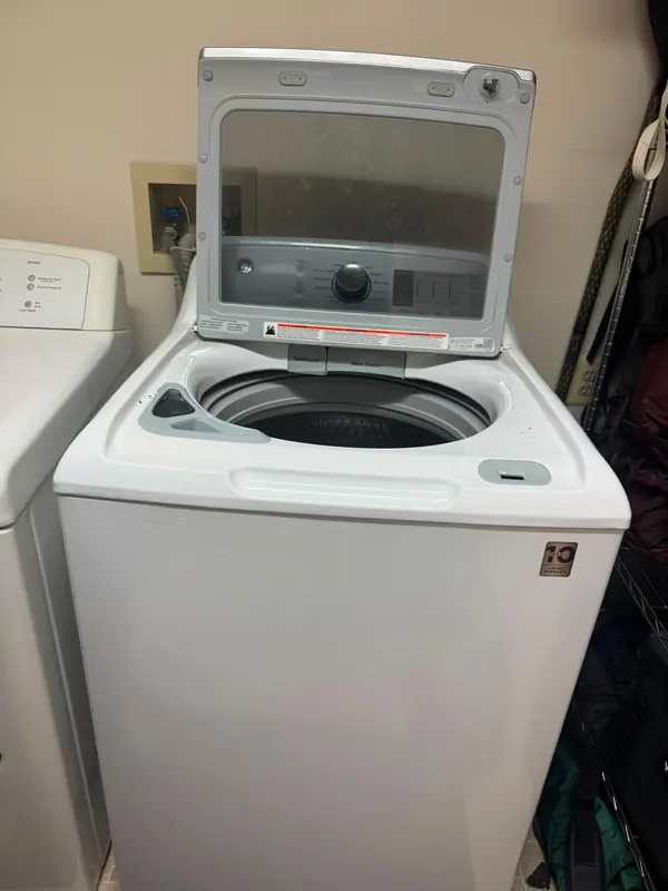 GE top-load washer with the lid open, showing the wash basket and the conditioner and water station dispensers