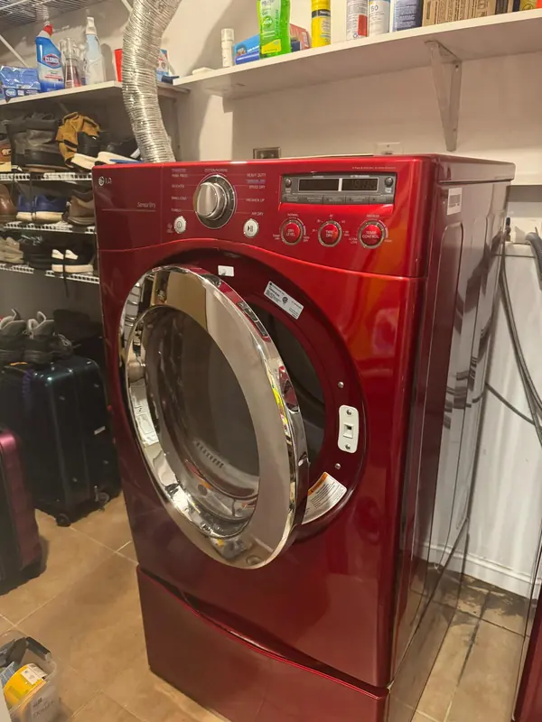 Red LG front-load dryer with Sensor Dry on a pedestal drawer, door open