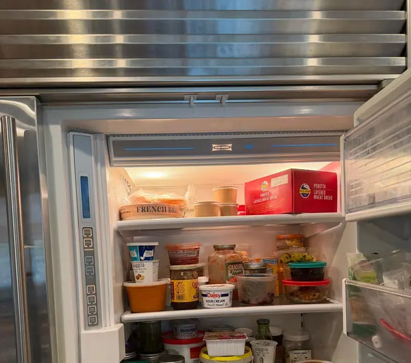 Inside a stocked Sub-Zero built-in refrigerator with the control panel on the left wall