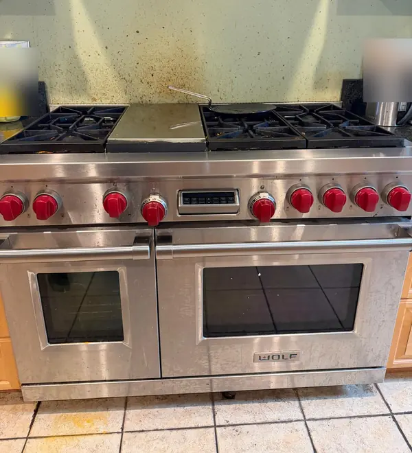 Wolf range with red knobs, six burners, a center griddle and two ovens